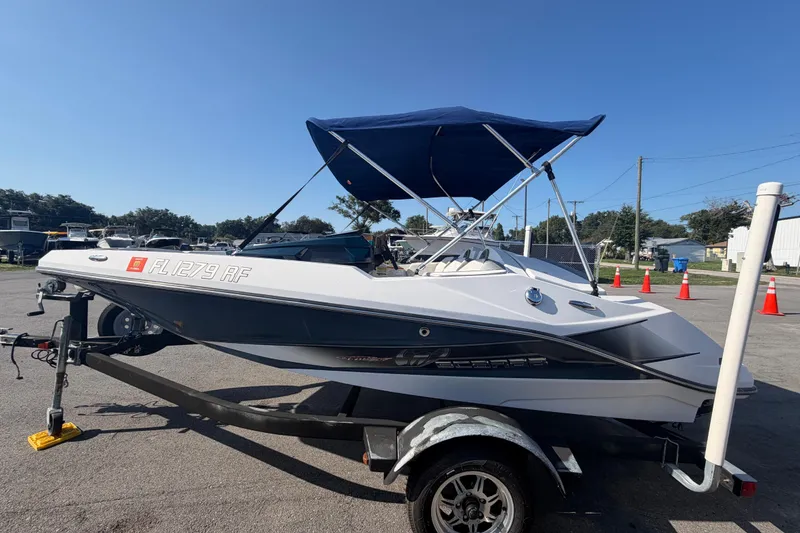 Slide: The Image of 2016 Scarab 165 boat with blue canopy on trailer, parked outdoors under clear sky. - 8