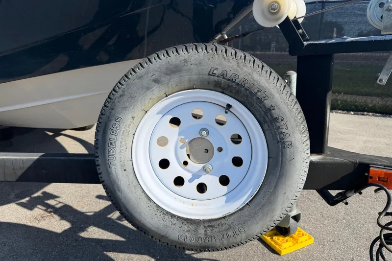 Slide: The Image of Trailer wheel of a 2016 Scarab 165 boat on pavement. - 56