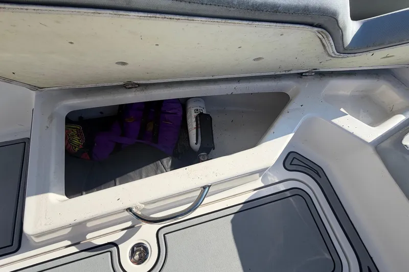 Slide: The Image of An open storage compartment on a 2016 Scarab 165 boat with a purple flotation device. - 31