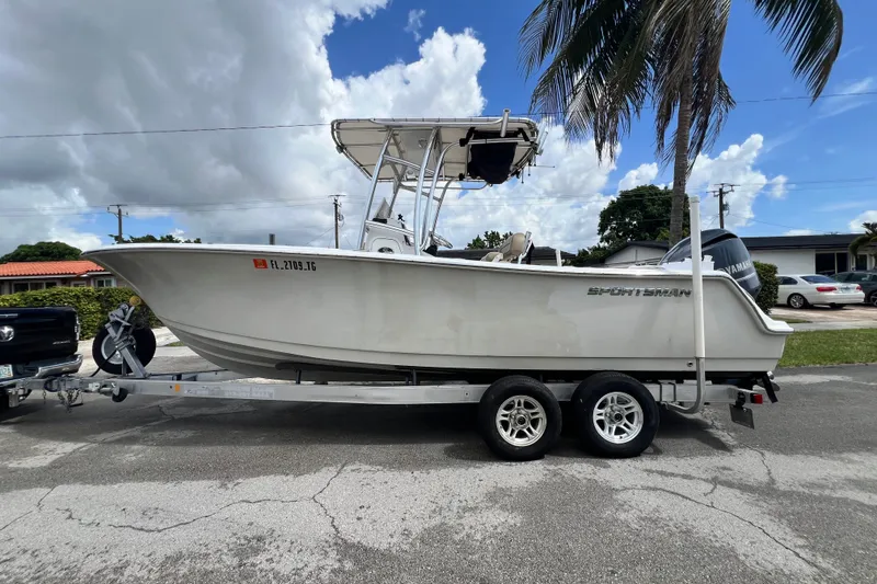 Slide: The Image of 2016 Sportsman Heritage 231 Center Console boat on trailer, parked under palm tree. - 1