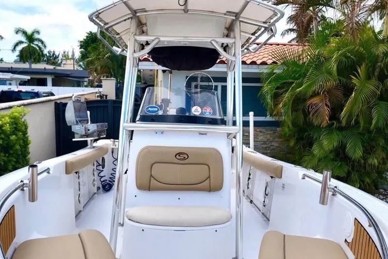 Slide: The Image of 2016 Sportsman Heritage 231 Center Console boat with seating and canopy, surrounded by tropical plants. - 40