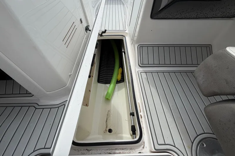 Slide: The Image of Storage compartment on 2016 Yamaha Boats 242 Limited S E-Series, featuring a green pool noodle. - 26