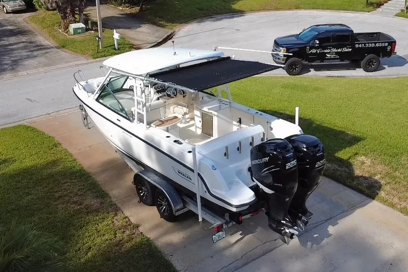 Slide: The Image of 2015 Boston Whaler 270 Vantage boat with dual Mercury engines on a driveway. - 32