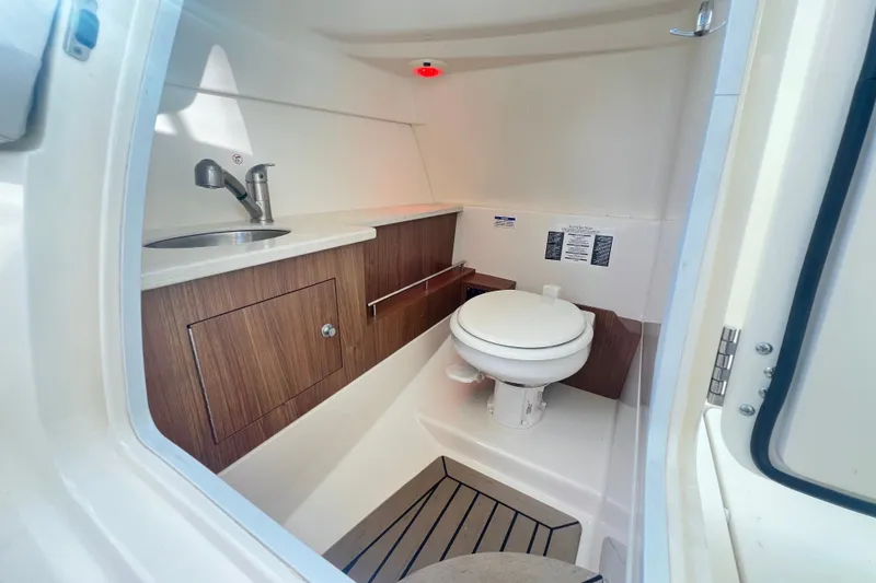 Slide: The Image of Interior of 2015 Boston Whaler 270 Vantage boat featuring a compact marine toilet and sink. - 88