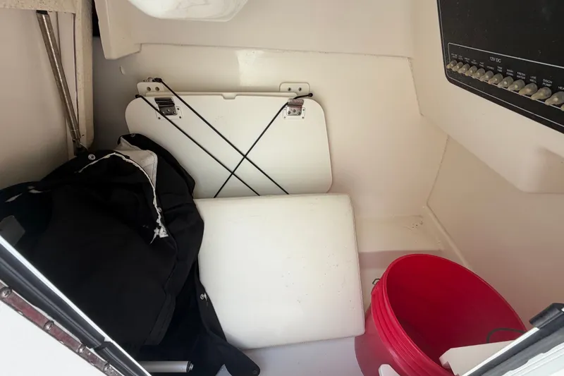 Slide: The Image of Interior storage of 2015 Boston Whaler 270 Vantage with red bucket and folded items. - 46