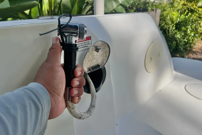 Slide: The Image of Hand holding a fuel nozzle on a 2015 Boston Whaler 270 Vantage boat. - 55