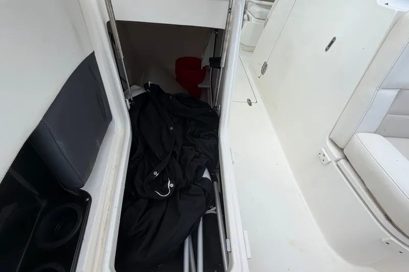 Slide: The Image of Storage compartment on a 2015 Boston Whaler 270 Vantage boat, containing black fabric and equipment. - 56