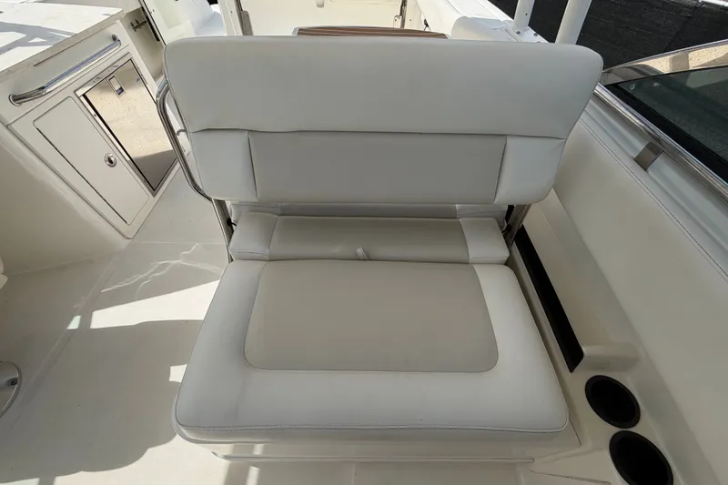 Slide: The Image of 2015 Boston Whaler 270 Vantage interior with white cushioned seating and storage compartments. - 62
