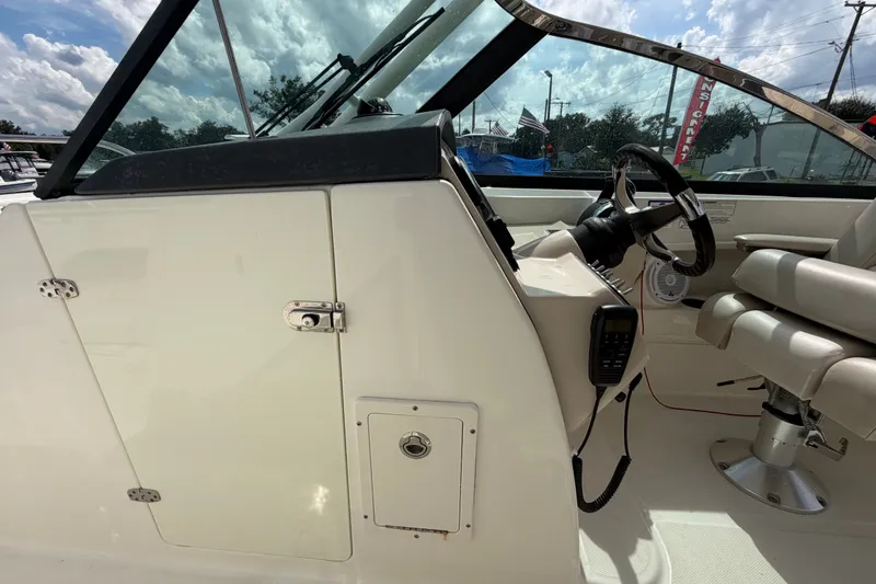 Slide: The Image of 2015 Boston Whaler 270 Vantage cockpit with steering wheel and seating under a sunny sky. - 44