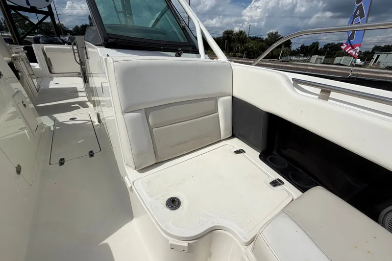 Slide: The Image of 2015 Boston Whaler 270 Vantage interior seating area with white upholstery and storage compartments. - 58
