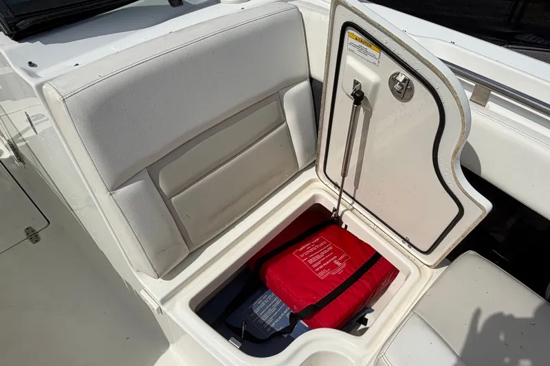 Slide: The Image of Storage compartment on a 2015 Boston Whaler 270 Vantage boat, containing a red life jacket. - 57