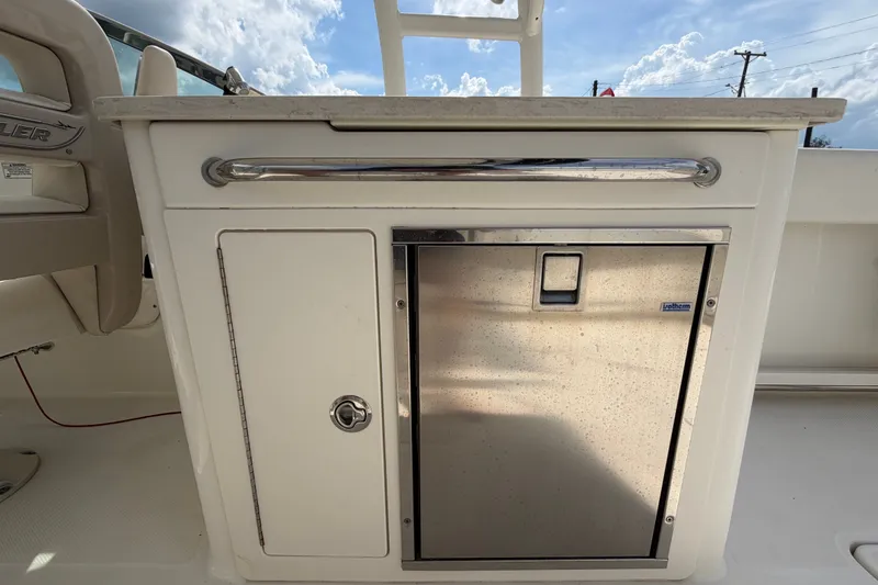 Slide: The Image of 2015 Boston Whaler 270 Vantage interior with stainless steel fridge and storage compartment. - 21