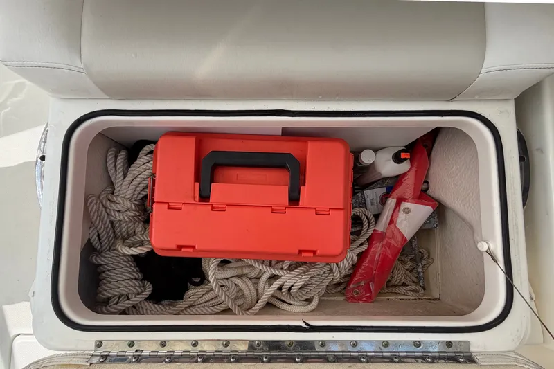 Slide: The Image of Storage compartment on a 2015 Boston Whaler 270 Vantage with ropes and a red toolbox. - 63