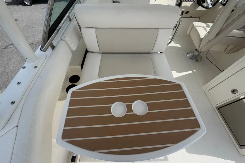 Slide: The Image of 2015 Boston Whaler 270 Vantage interior with cushioned seating and wooden table. - 19
