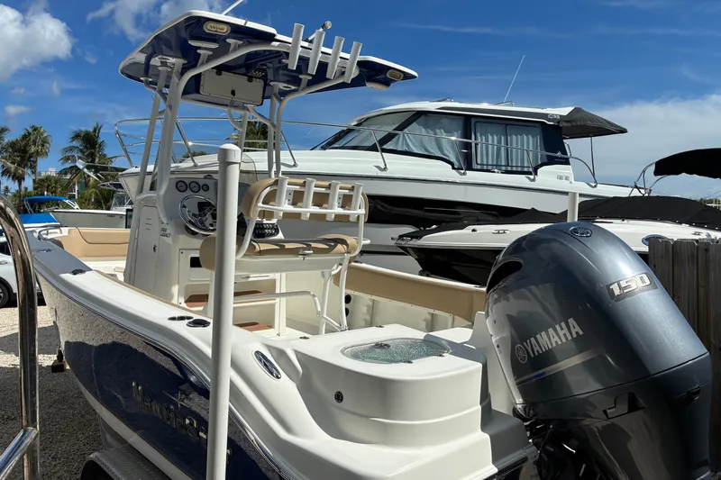 Slide: The Image of 2019 NauticStar 2102 Legacy boat with Yamaha 150 engine, docked under clear blue sky. - 1