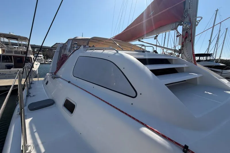 Slide: The Image of 2000 Leopard 38 catamaran with red sail, docked in marina under clear sky. - 102