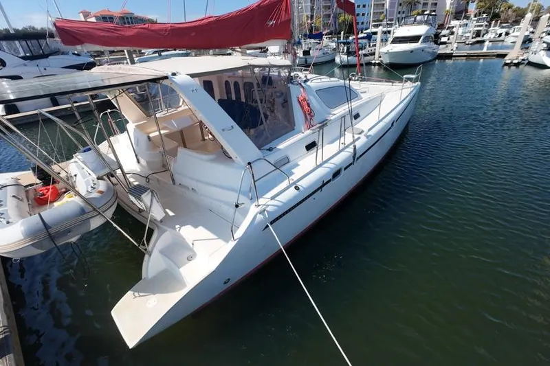 Slide: The Image of 2000 Leopard 38 catamaran docked in marina with red sail and dinghy. - 15