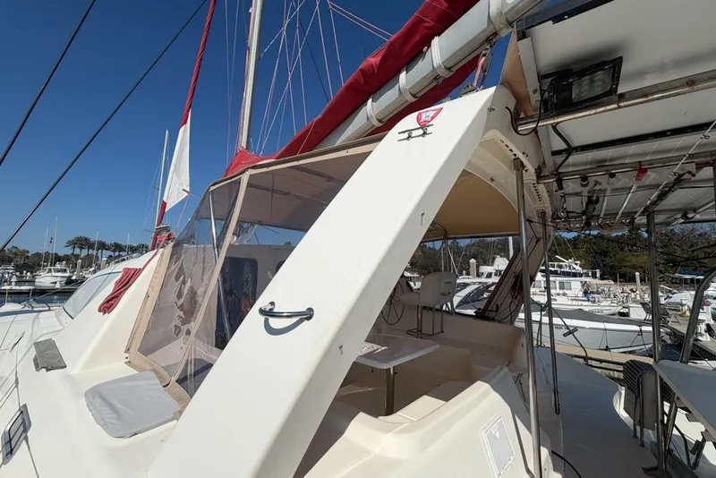 Slide: The Image of 2000 Leopard 38 catamaran with red sails docked at a marina under clear blue skies. - 91