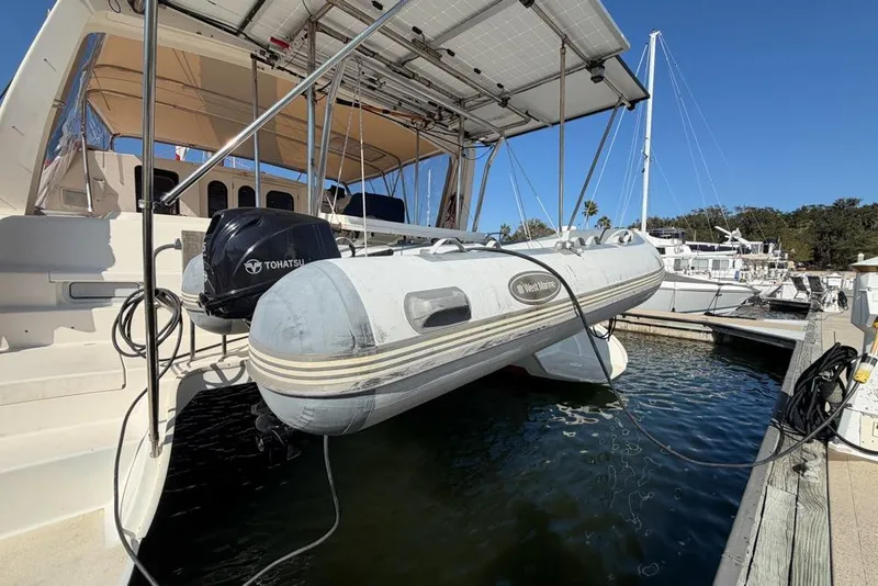 Slide: The Image of Leopard 38 catamaran with dinghy and Tohatsu motor at marina, 2000 model. - 153