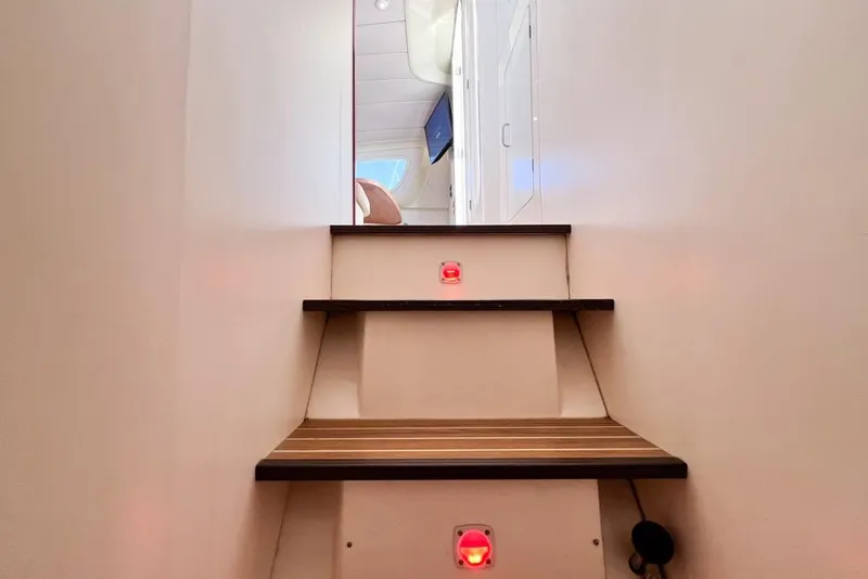 Slide: The Image of Staircase inside 2000 Leopard 38 yacht, featuring wooden steps and red lights. - 62