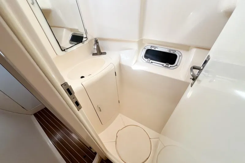 Slide: The Image of Compact bathroom in a 2000 Leopard 38 yacht with sink, mirror, and porthole. - 52