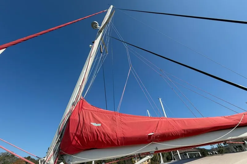 Slide: The Image of Sailboat with red sail cover, Leopard 38 model, 2000, against clear blue sky. - 137