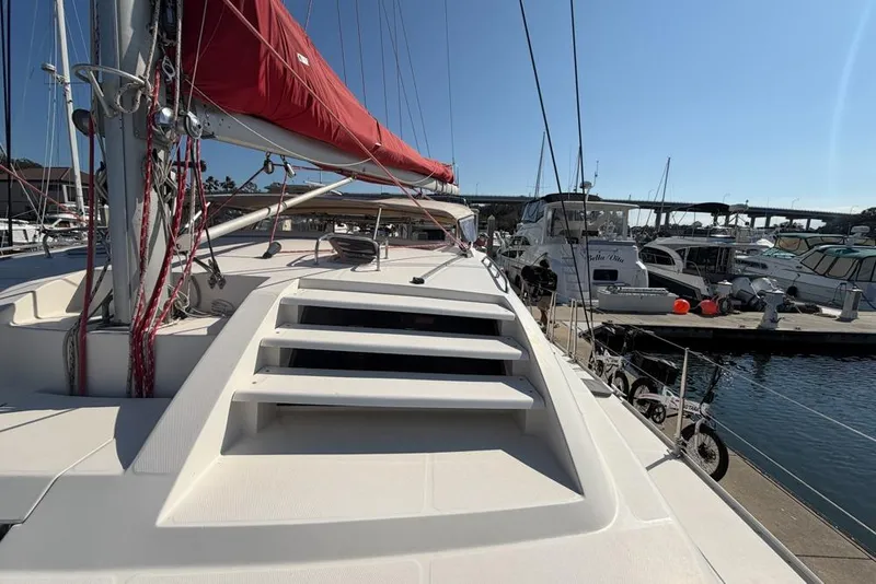 Slide: The Image of 2000 Leopard 38 catamaran with red sail docked at marina, surrounded by boats. - 119