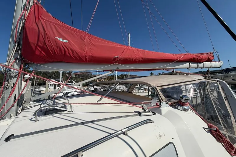 Slide: The Image of Sailboat with red sail cover, Leopard 38 model, 2000, docked in marina under clear sky. - 136