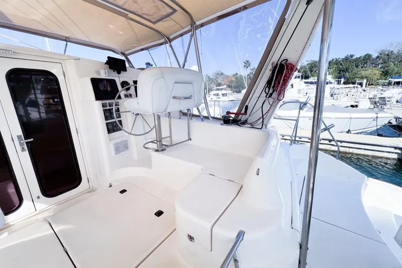 Slide: The Image of Helm station of 2000 Leopard 38 catamaran with white seating and marina view. - 23