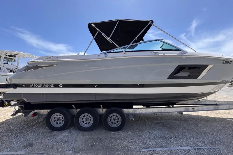 Slide: The Image of 2015 Four Winns H290 boat on trailer under clear blue sky. - 14