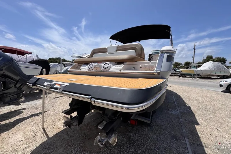 Slide: The Image of 2015 Four Winns H290 boat with dual engines, parked on gravel under a clear blue sky. - 17