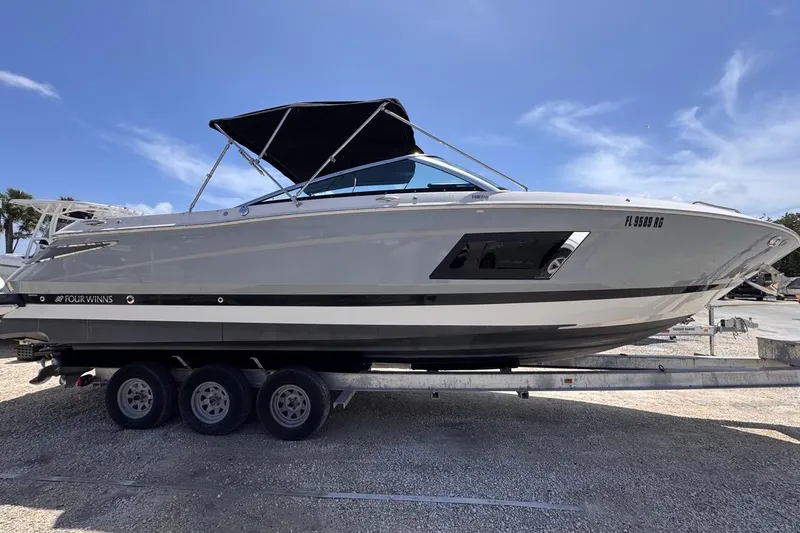 Slide: The Image of 2015 Four Winns H290 boat on trailer under clear blue sky. - 13