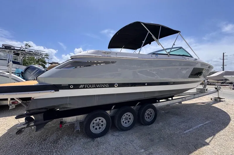 Slide: The Image of 2015 Four Winns H290 boat on trailer under clear blue sky. - 15