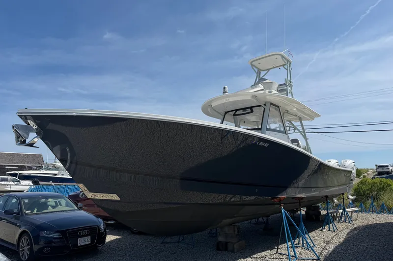 Slide: The Image of 2019 Regulator 41 boat on stands, parked near a car, under a clear blue sky. - 1