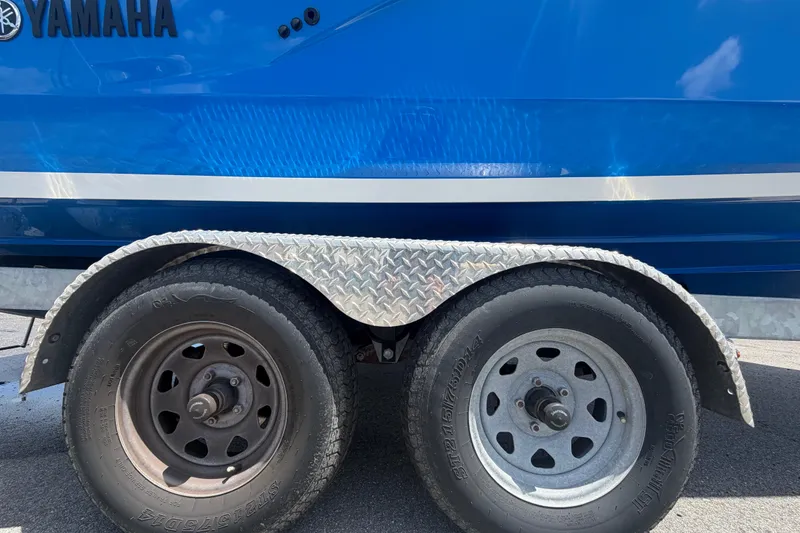 Slide: The Image of 2024 Yamaha Boats 222XD trailer with dual wheels and blue hull. - 85