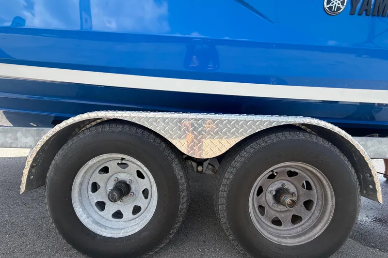 Slide: The Image of Trailer wheels and fender of a 2024 Yamaha Boats 222XD, with blue hull background. - 86