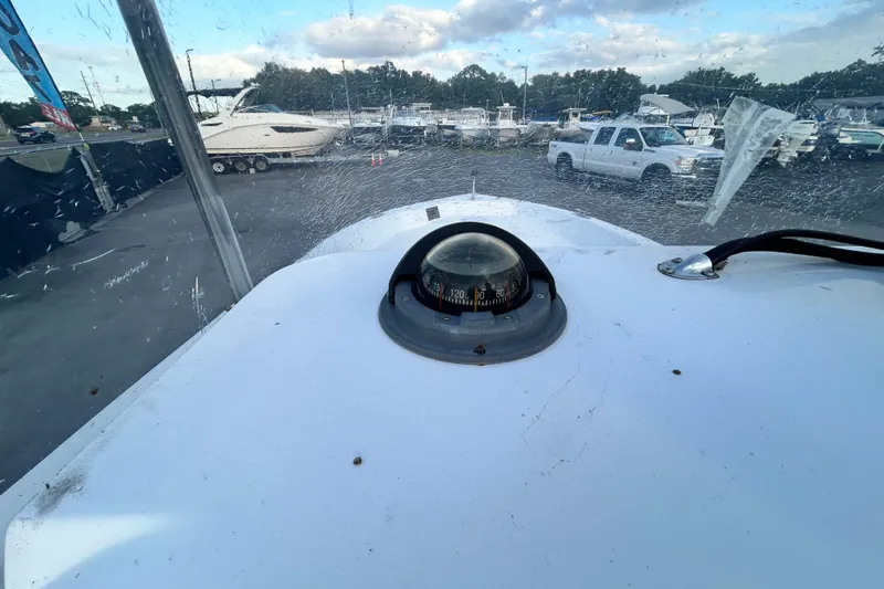 Slide: The Image of 1999 Hydra-Sports 2000 CC boat dashboard with compass, parked near other boats and vehicles. - 19