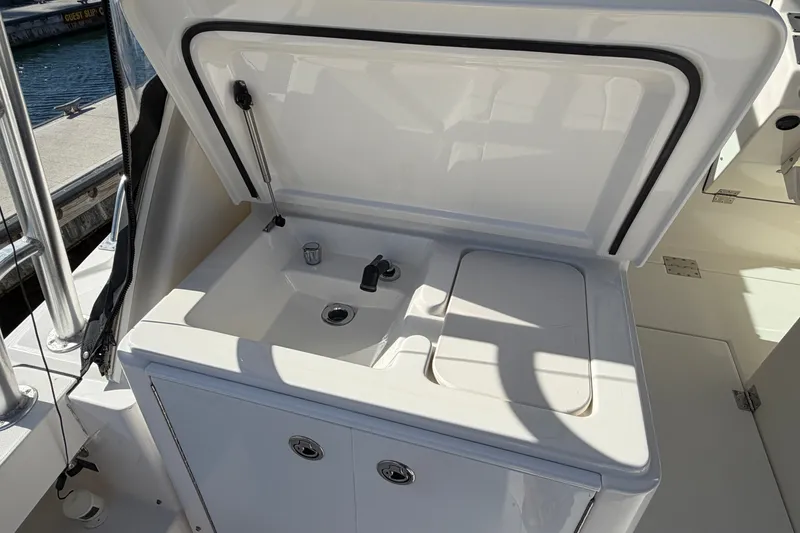 Slide: The Image of 2007 Rampage 30 Express boat sink and storage area, open lid, dockside view. - 25