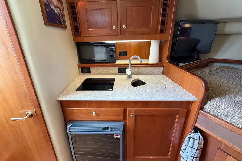 Slide: The Image of Compact kitchen area in a 2007 Rampage 30 Express boat with sink, microwave, and fridge. - 49