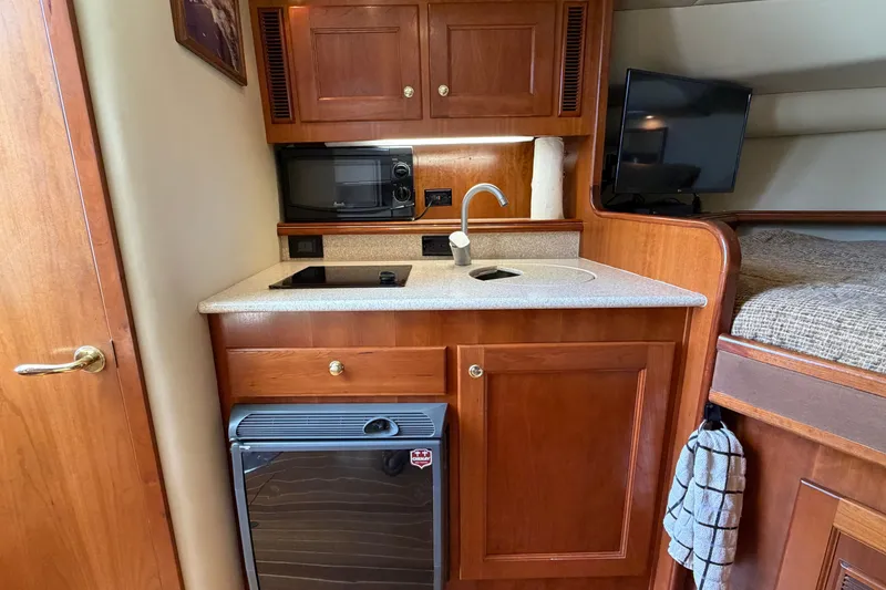 Slide: The Image of Compact kitchen area in a 2007 Rampage 30 Express boat with wood cabinetry and appliances. - 48