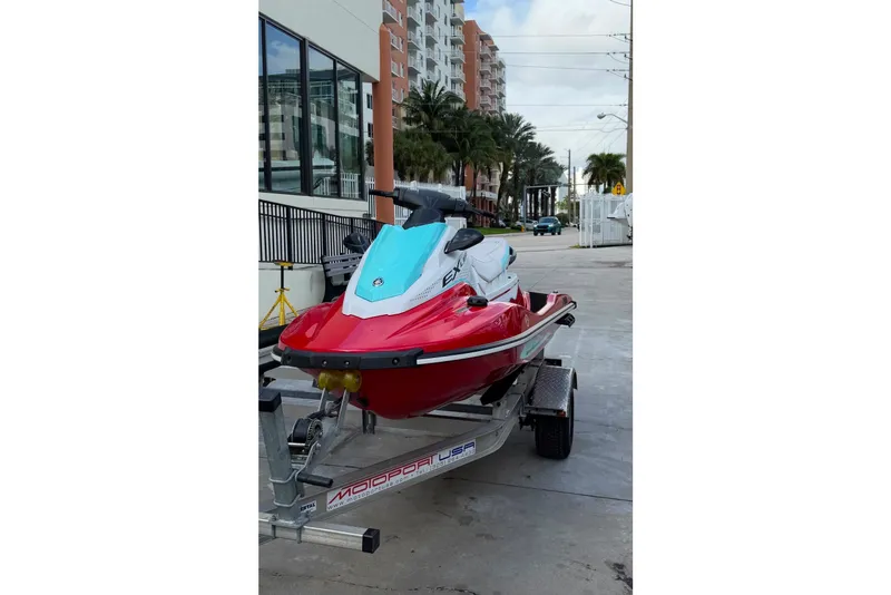 Slide: The Image of 2024 Yamaha WaveRunner EX Limited on trailer, urban background, vibrant red and blue design. - 1