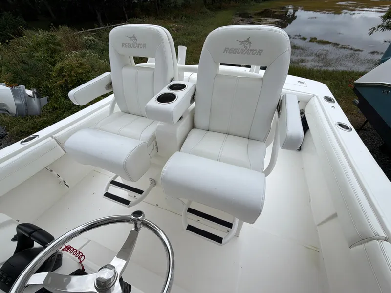 Slide: The Image of Two white captain's chairs on a boat with a steering wheel and cup holders. - 28