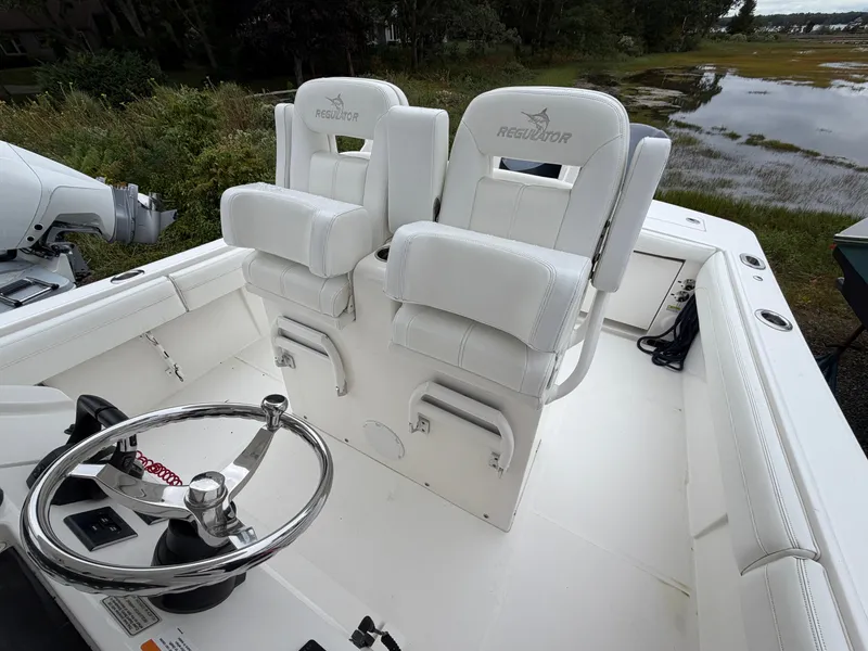 Slide: The Image of Two white captain's chairs on a boat with a helm and natural scenery in the background. - 27