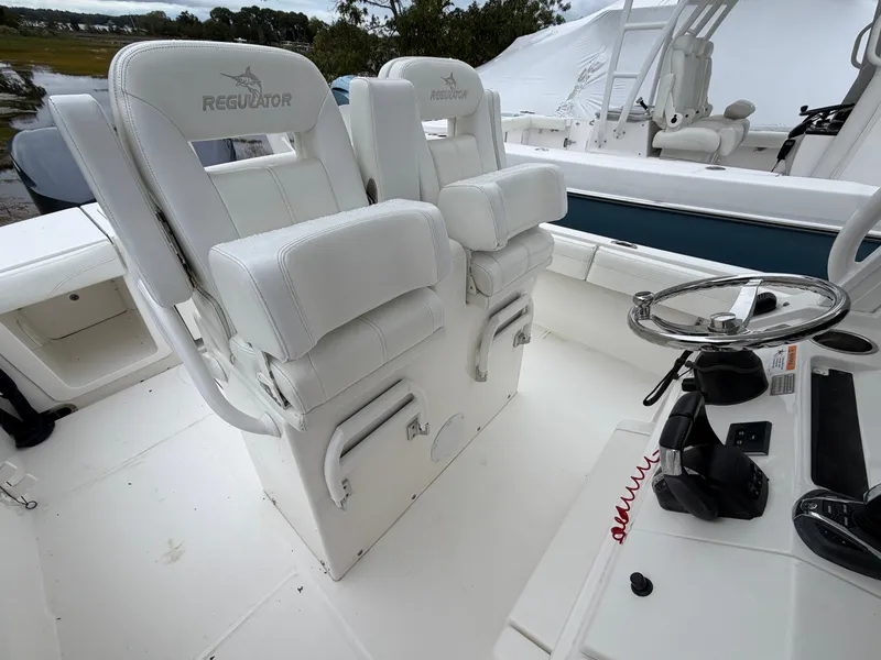 Slide: The Image of The image shows the cockpit of a 2021 Regulator 28 boat with white seats and a helm console. - 26