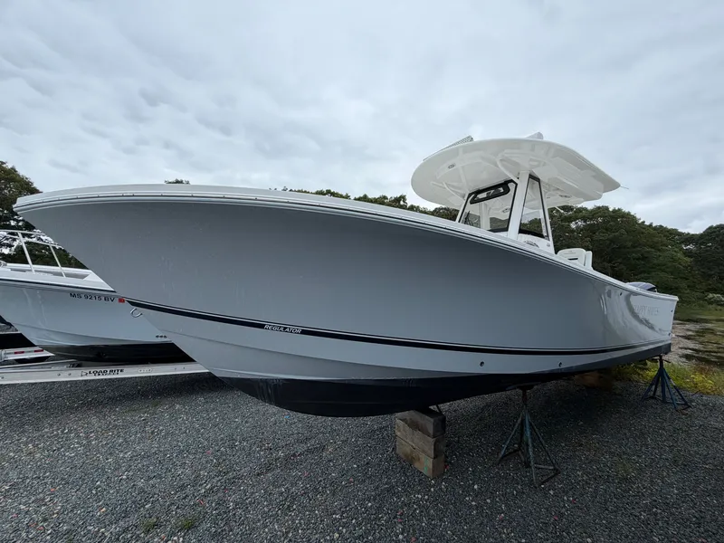 Slide: The Image of 2021 Regulator 28 on a stand, gray hull, white top, cloudy sky. - 6
