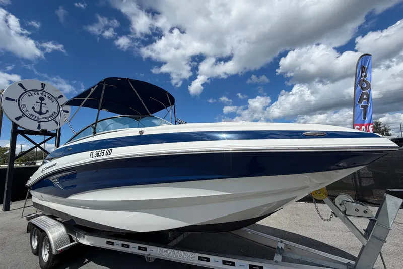 Slide: The Image of 2023 Crownline Eclipse E235 XS boat on trailer under blue sky. - 0
