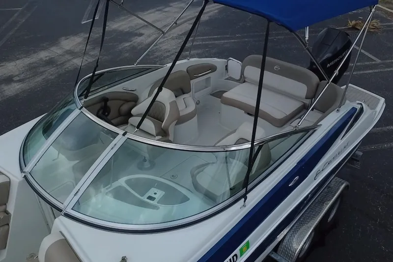 Slide: The Image of 2023 Crownline Eclipse E235 XS boat with blue canopy and spacious seating. - 13