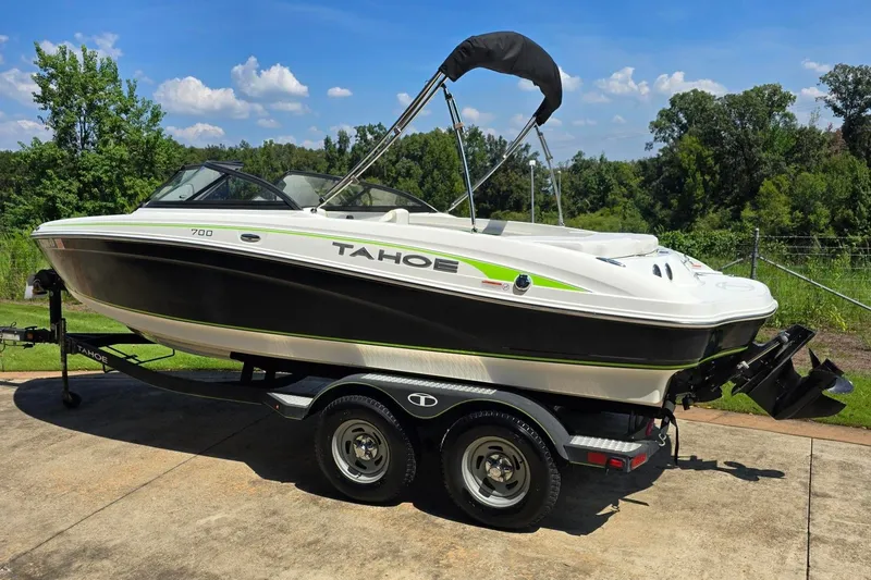 Slide: The Image of 2018 Tahoe 700 boat on trailer, parked outdoors under a clear blue sky. - 5