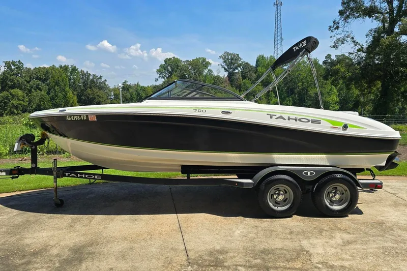 Slide: The Image of 2018 Tahoe 700 boat on trailer, parked outdoors with lush greenery in the background. - 6
