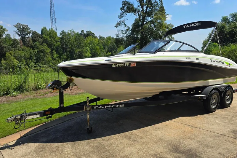 Slide: The Image of 2018 Tahoe 700 boat on trailer, parked outdoors with lush greenery background. - 7